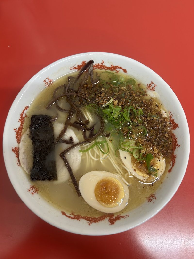 赤いテーブルの上の、煮たまごと海苔、きくらげをのせたラーメン