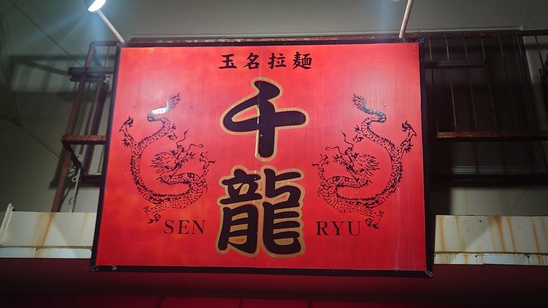 夜に明かりのともった、二頭の龍の赤い「千龍」の看板